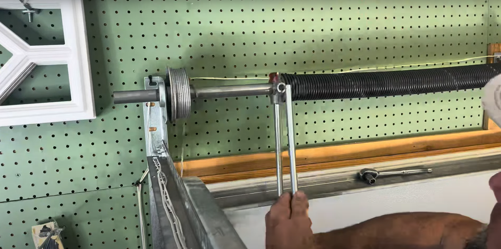 A professional garage door technician repairing the springs of a garage door to enhance home security."