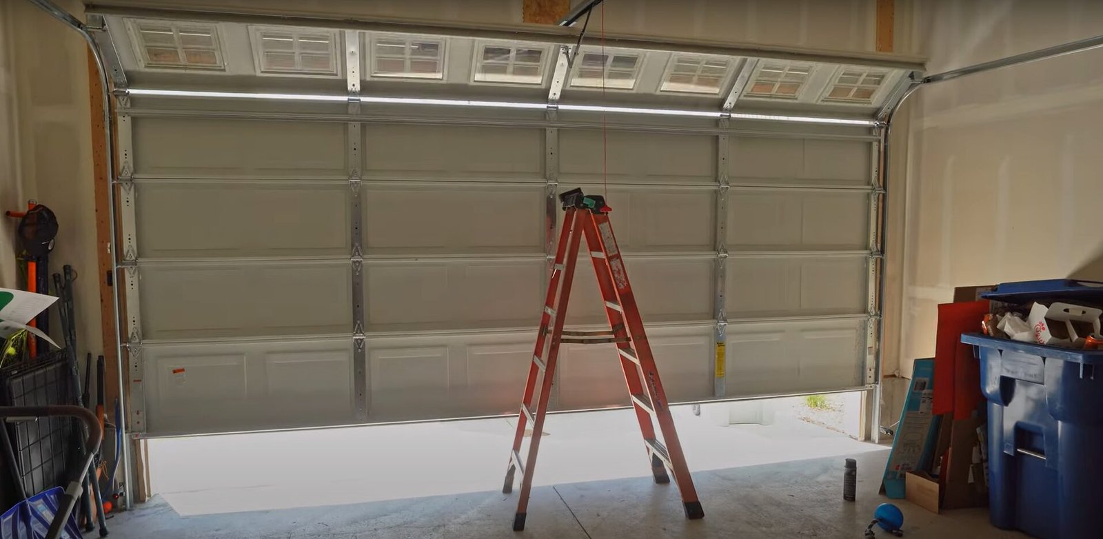 Professional inspecting a rusted garage door track due to high humidity.