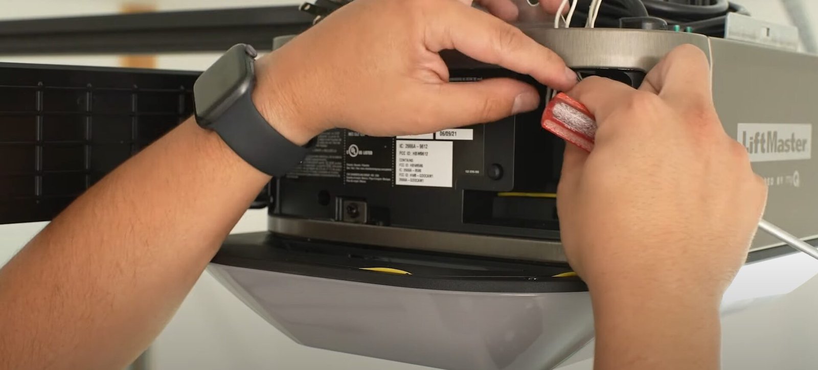 A professional technician from Garage Door Repair Miami Gardens LLC repairing a garage door opener to improve system efficiency.